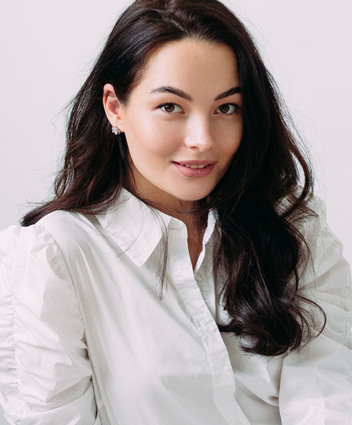 Young woman in white shirt, smiling confidently.