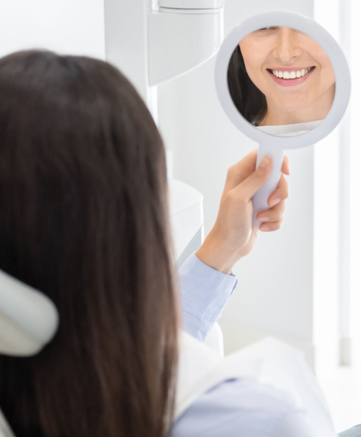Patient admiring her smile in a dental office.