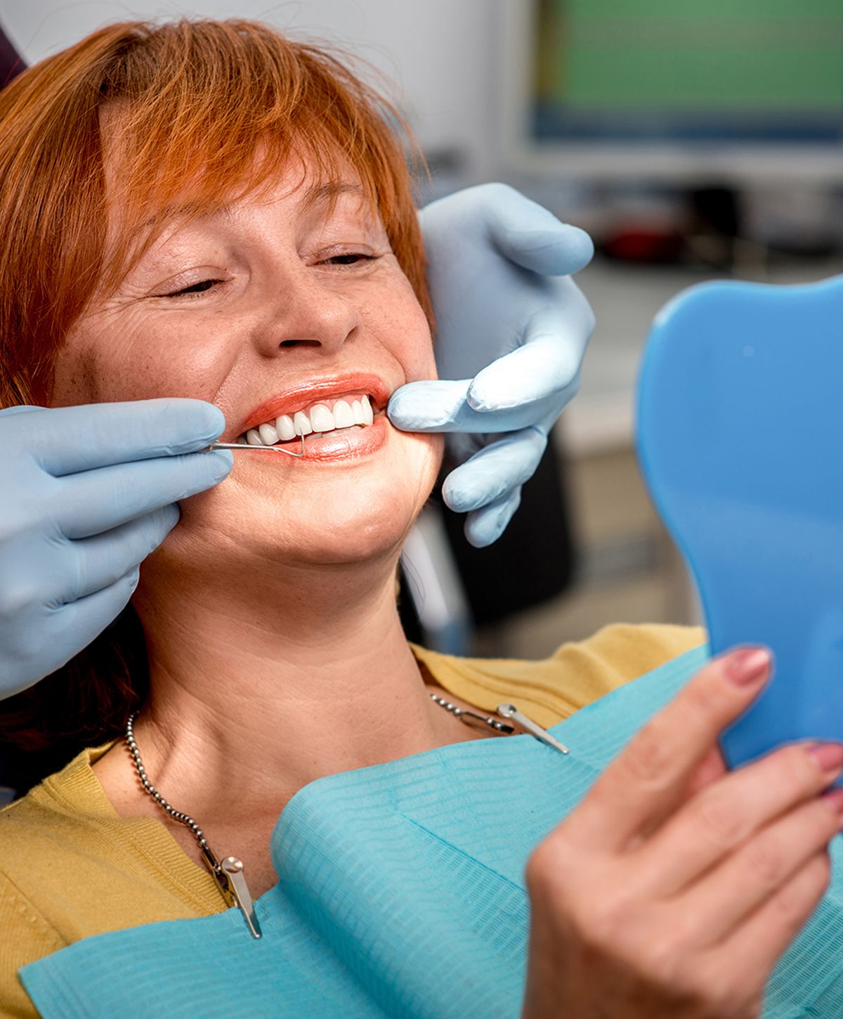 Smiling woman with wavy red hair in sweater.