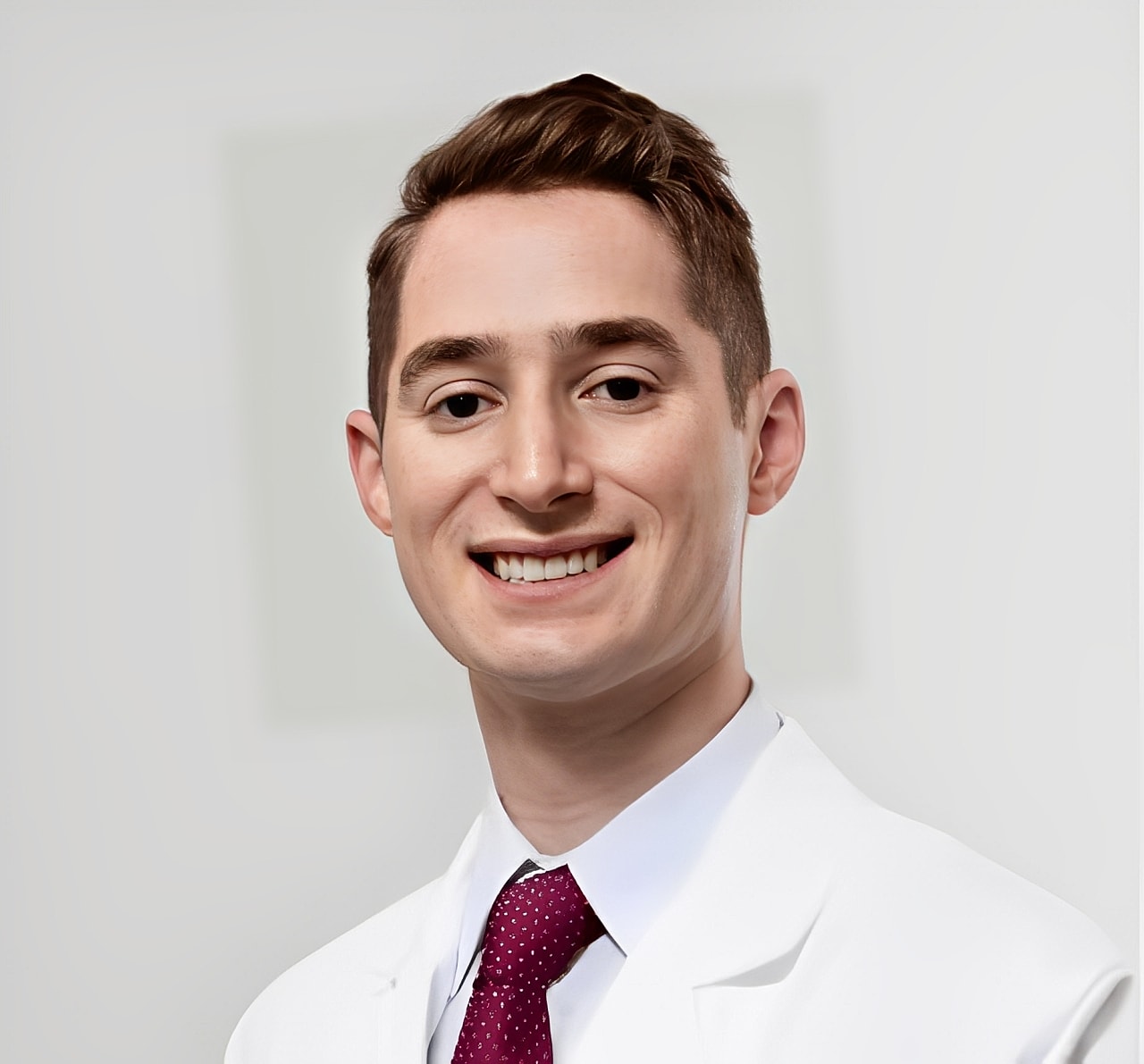 Smiling professional in a white coat and tie.