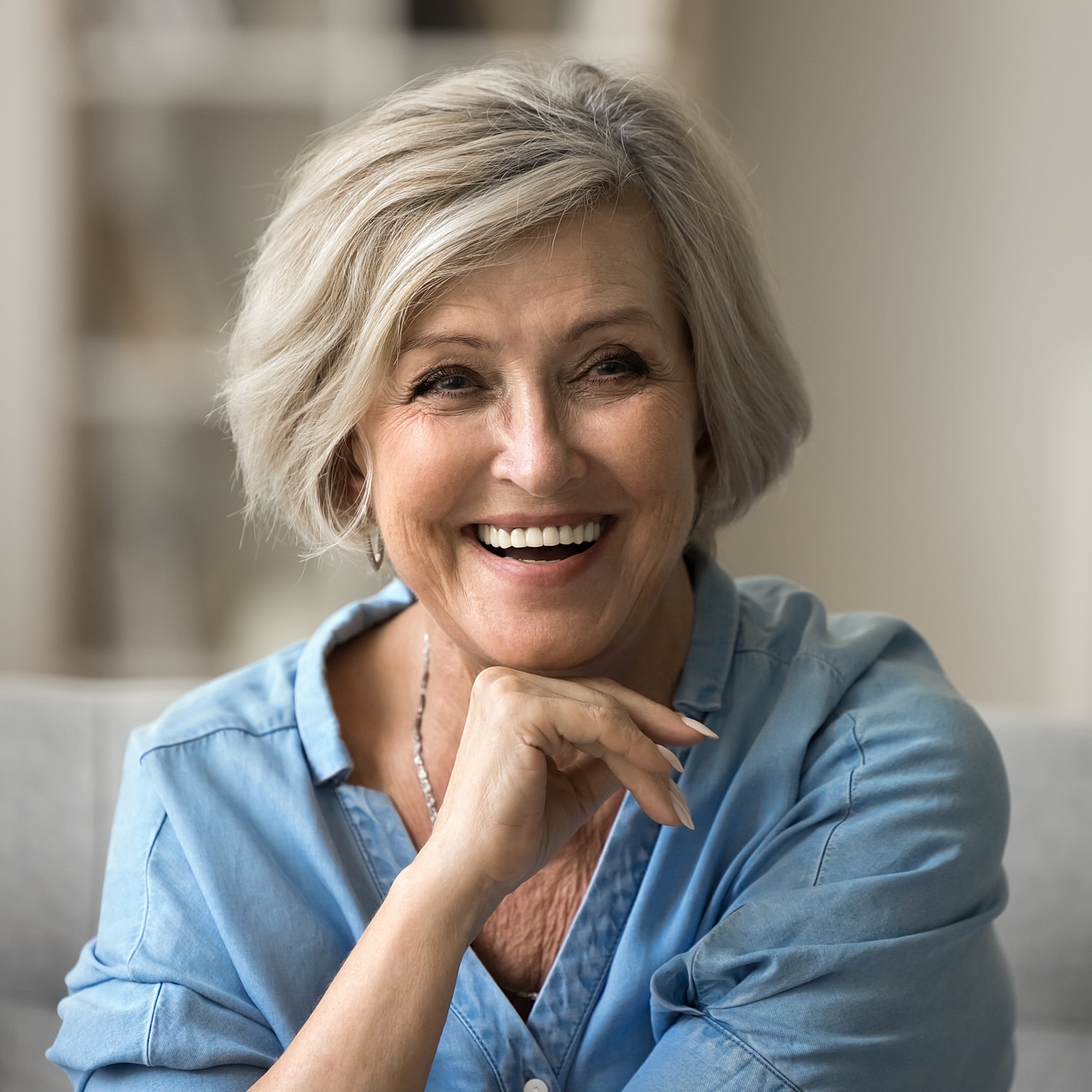 Smiling senior woman in casual blue shirt with full mouth dental implants Brighton