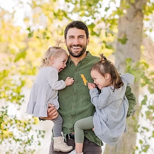 Father playing with two joyful daughters outdoors.
