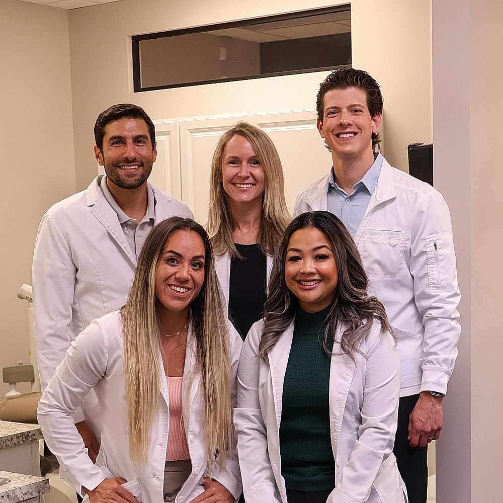 Smiling woman in a pink top, dental office background.