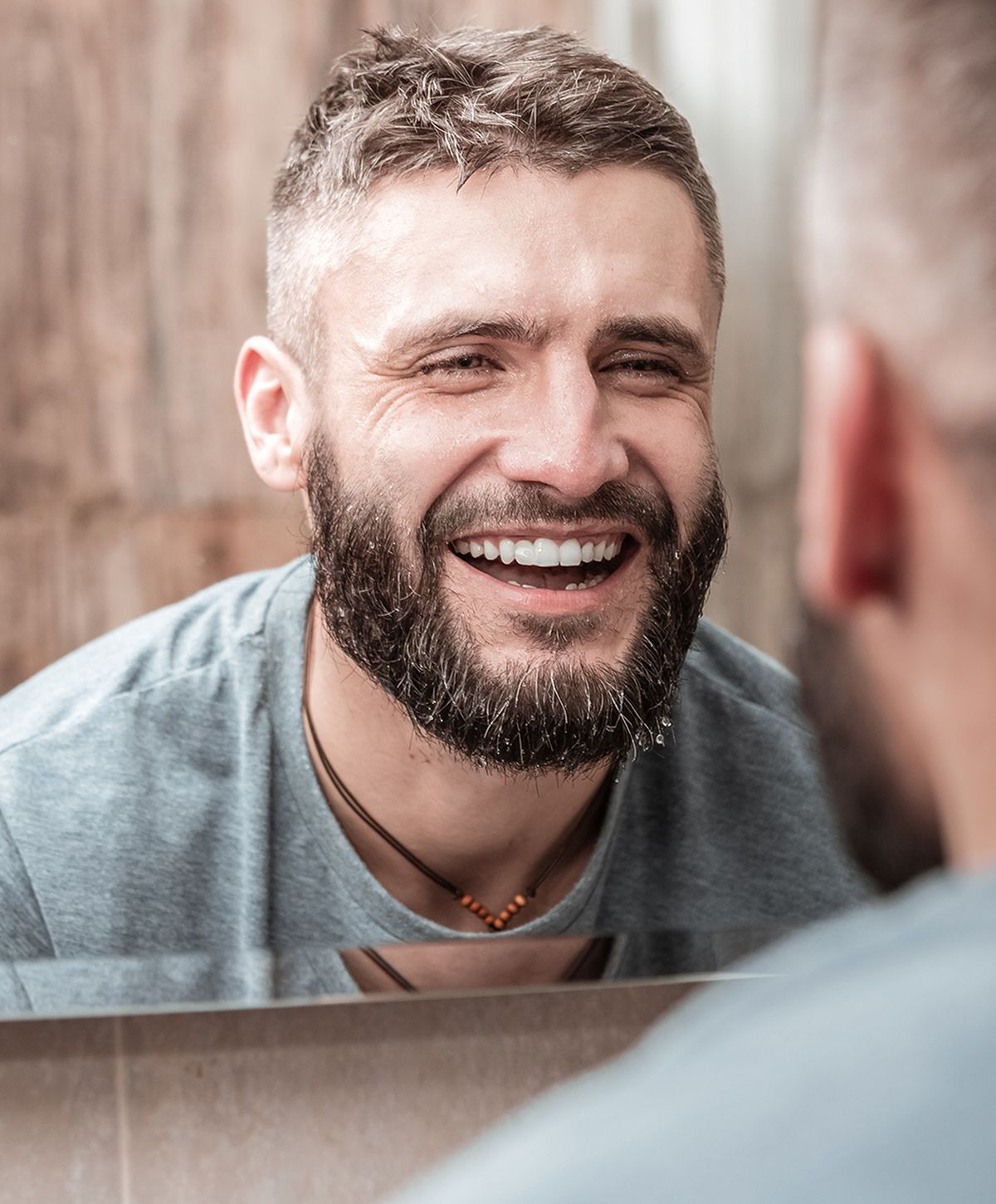 Man smiling in front of a mirror.
