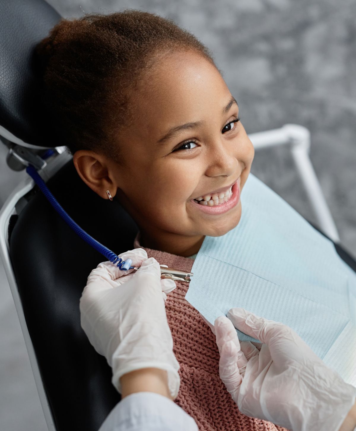 Child smiling in dental chair during check-up.