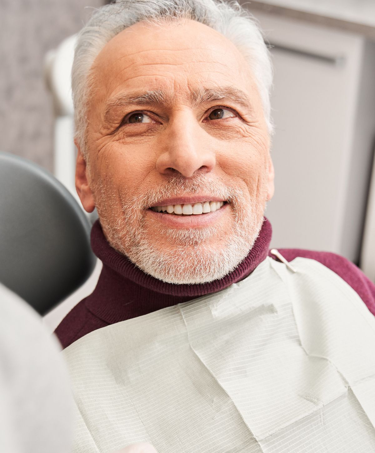 Smiling man in dentist's chair, relaxed atmosphere.