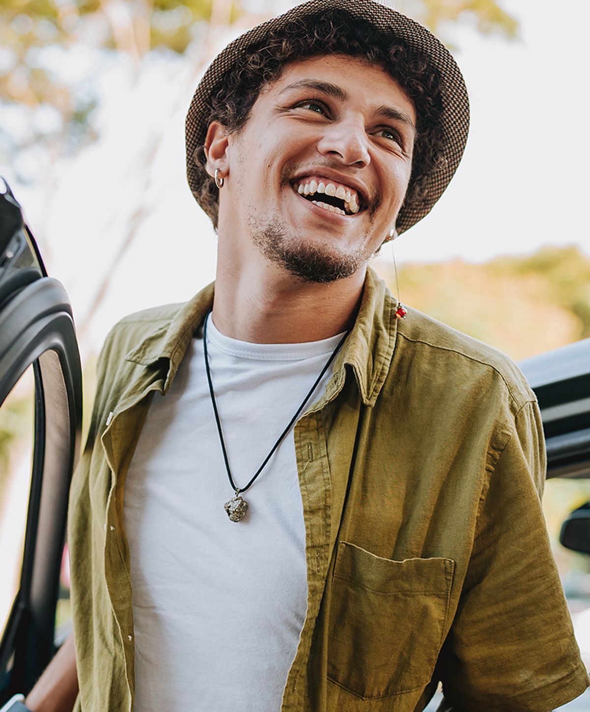 Smiling man wearing a denim shirt outdoors.