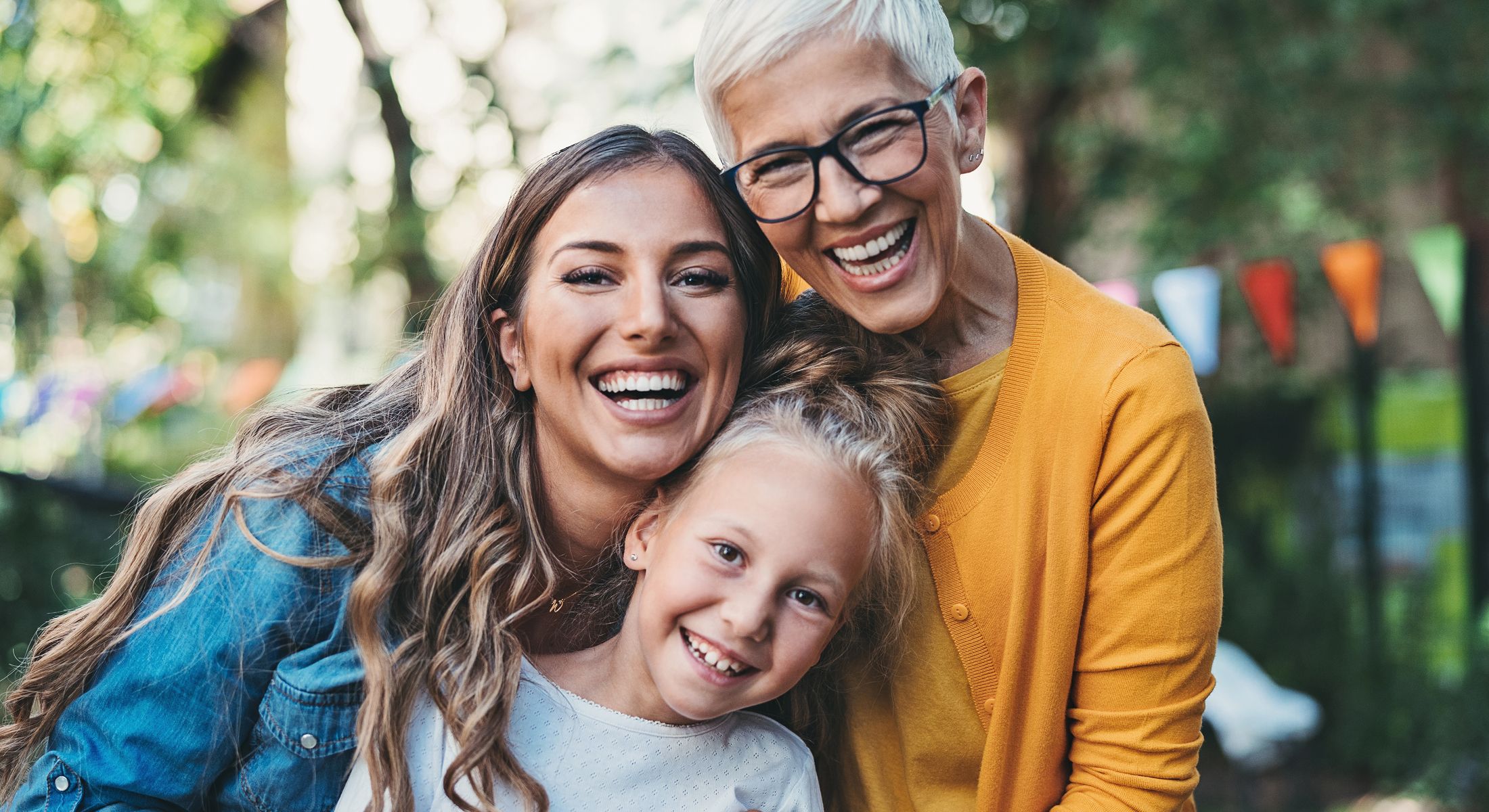 Three generations of smiling women outdoors.