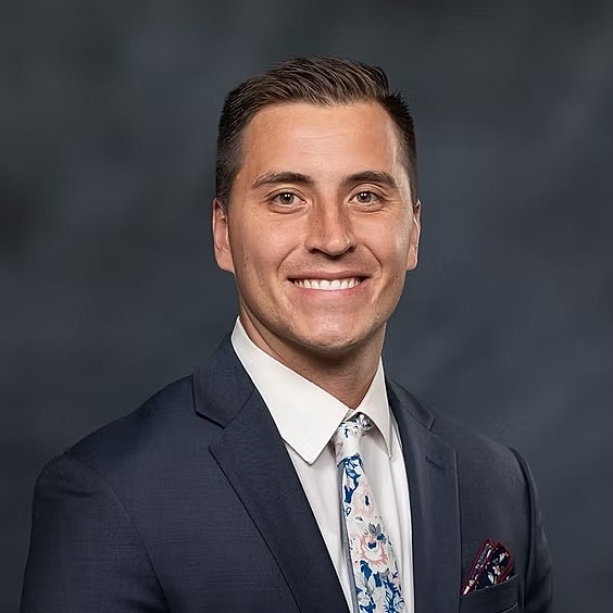 Smiling man in a suit with a floral tie.