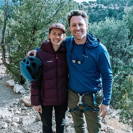 Two climbers smiling outdoors in nature.