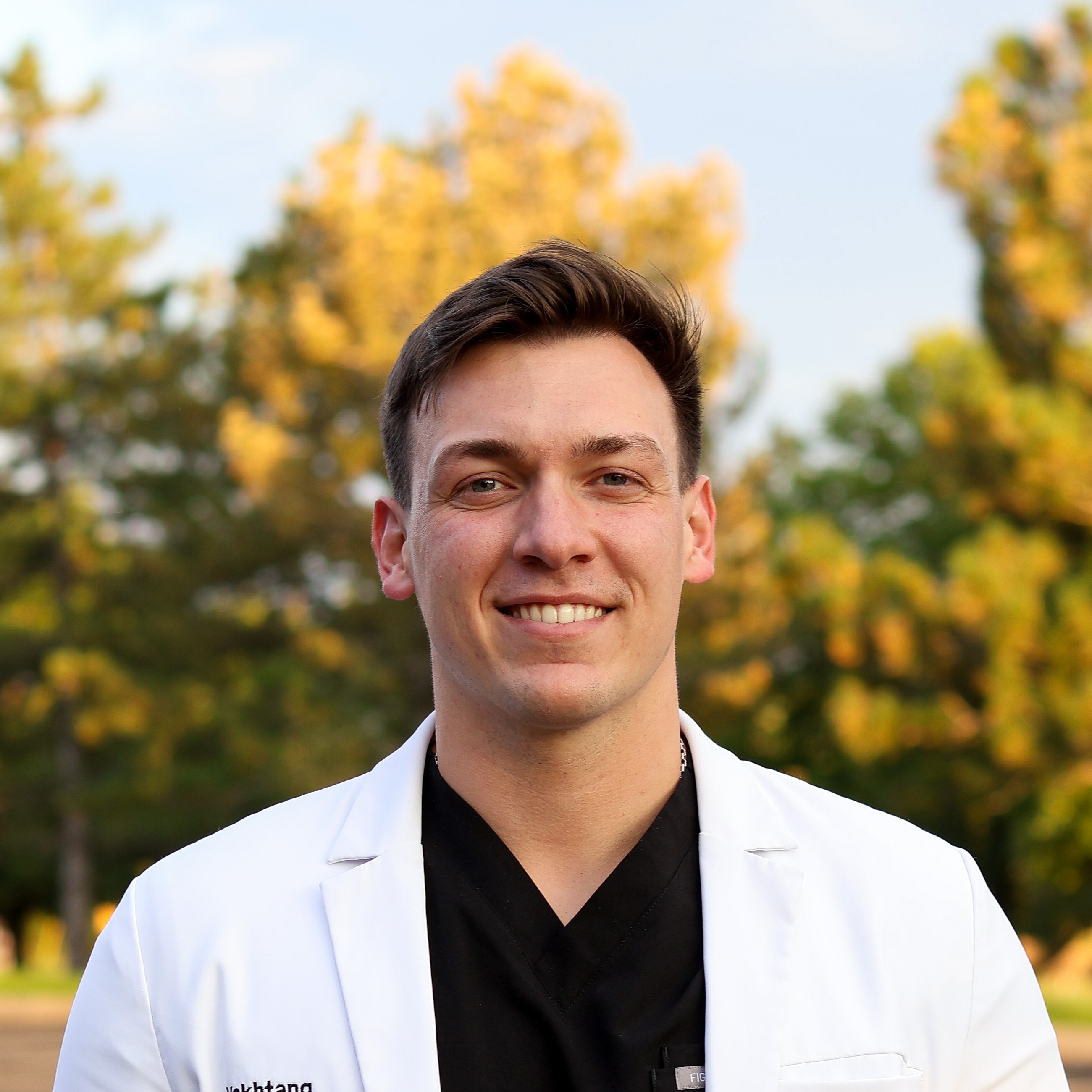 Smiling man in formal attire against gray background.