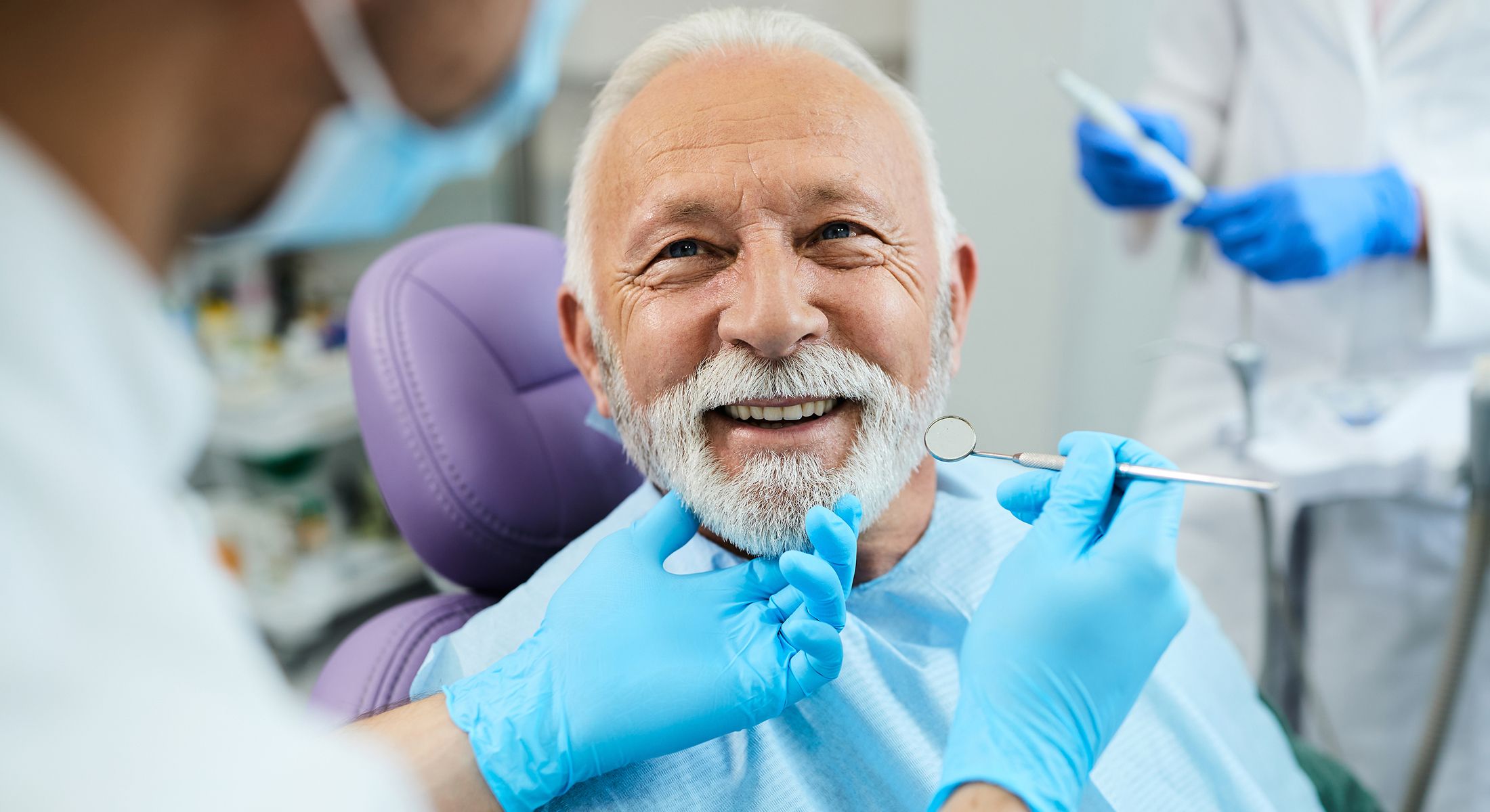 Dentist examining elderly man's teeth and smile.